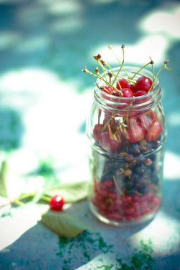 kiraz ve bir kavanoz mavi masa üzerinde kuş üzümü