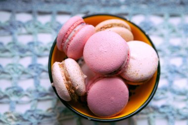Mavi dantel zemin üzerine sarı bir kasede macaroons