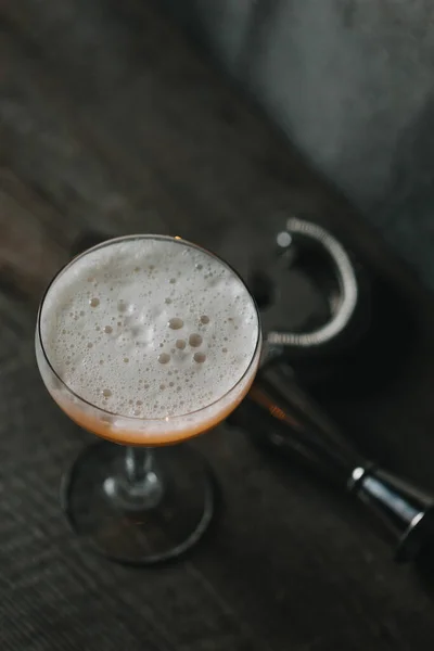 Alcohol whiskey sour cocktail in a coupe glass with jigger and strainer. Drink in the bar — Stock Photo, Image