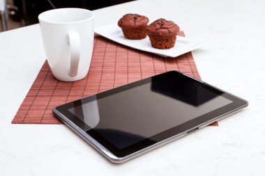 bir fincan kahve ve bir tablet pc ile kek çikolata cips