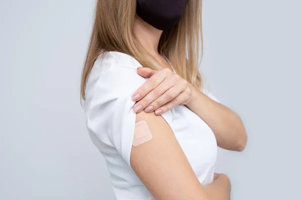 Unerkennbare Frau ohne Gesicht und weißes T-Shirt mit Pflaster an der Hand freut sich über eine Impfung gegen die Coronavirus-Infektion Covid-19. Kopierraum. . — Stockfoto