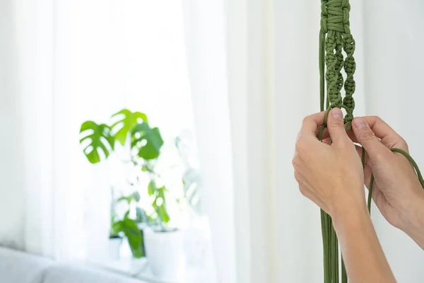 На женской руке висят вешалки из зеленого макраме ручной работы с горшечным растением. горшок и монстры — стоковое фото
