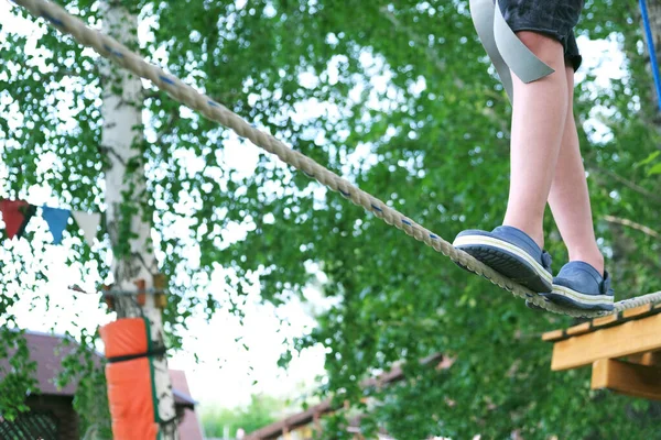 Menino se divertindo no verão no parque de aventura na tirolesa. Feixe de equilíbrio e pontes de corda — Fotografia de Stock