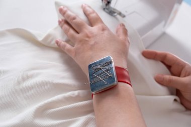 Gerçek bir orta yaşlı kadın evde dikiş makinesi kullanarak elbise dikiyor. Terzi çalışıyor. Ev içinde el yapımı kıyafetler. Kadın oturmuş dikiş dikmenin tadını çıkarıyor.. 