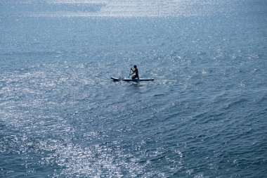 Çocuklu genç bir sporcu denizde sup ile denize açılır. Sağlıklı yaşam tarzı kavramı
