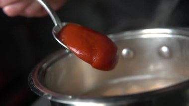 Mutfakta metal bir tencerede domates çorbası pişirmek. Sıcak suyla birlikte metal kaşıktan dökülen domates soslu ev çorbası. Geleneksel mutfak. 