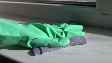 Kadın avuç içi lastik eldivenle beyaz plastik pencere pervazını ıslak bezle siliyor. Güneşli bir günde ev temizliği..