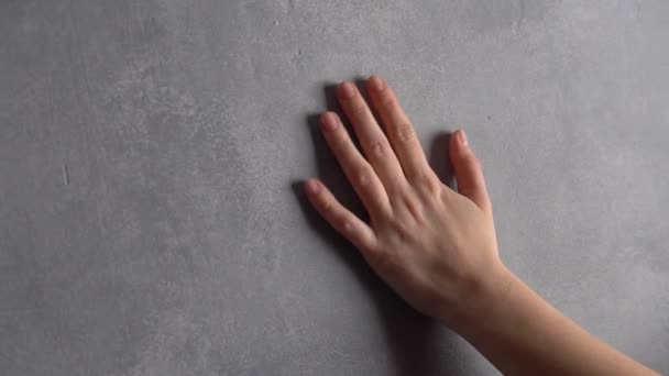 女性の手の手のひらは灰色のコンクリート石膏塗装ホールの壁の表面に触れている — ストック動画