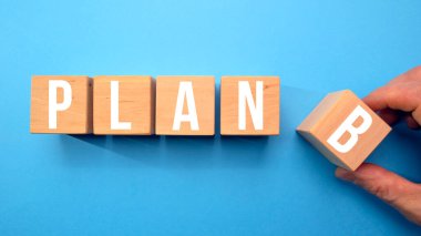 Plan B 'yi temsil eden beş tahta küp mavi bir arkaplanda izole edilmiş. B planı tahta küplere beyaz harflerle yazılmıştır. Strateji, analiz, pazarlama, proje ve kriz konsepti. Boşluğu kopyala.