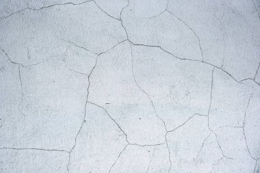 Beyaz, gri beton duvar, zeminde çatlaklar, doku arkaplan. Kırık beyaz alçı duvar. Beyaz çatallı duvar. Kırık beyaz duvar dokusu.