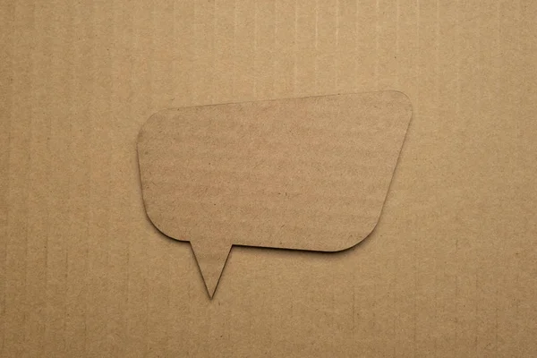 Speech bubble crepe paper balloon label on cardboard background with shadow. Blank speech bubble on paper background.