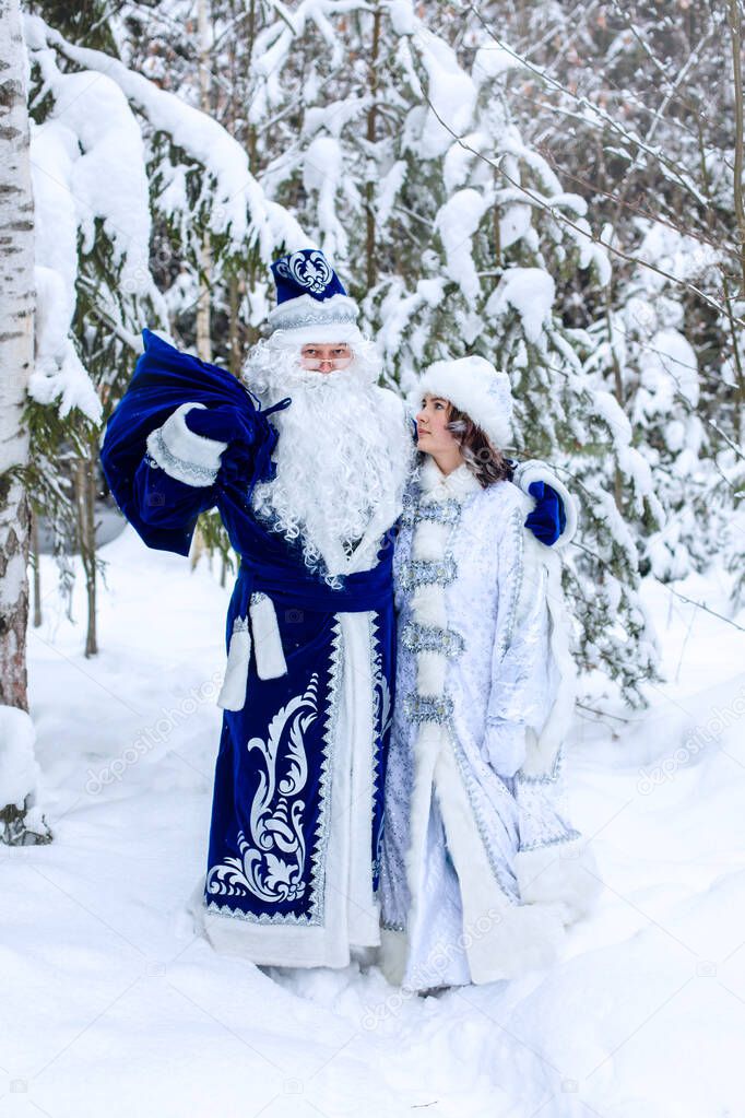 Russian Christmas characters Ded Moroz (Father Frost) and Snegurochka (Snow Maiden). Father Frost with a bag of gifts and a Snow Maiden in the forest.  Winter, December. Christmas card.