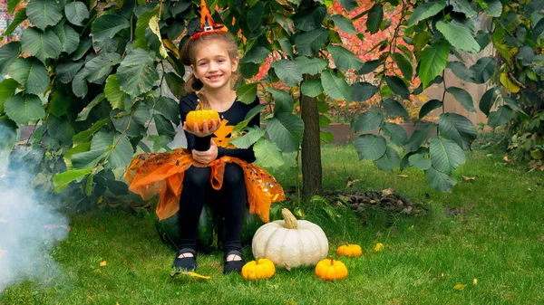 Little Witch Sits Pumpkin Autumn Garden Girl Dressed Witch Halloween — Stock Photo, Image