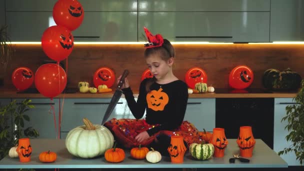 La chica triste con un cuchillo no quiere cortar la calabaza en Halloween. — Vídeos de Stock