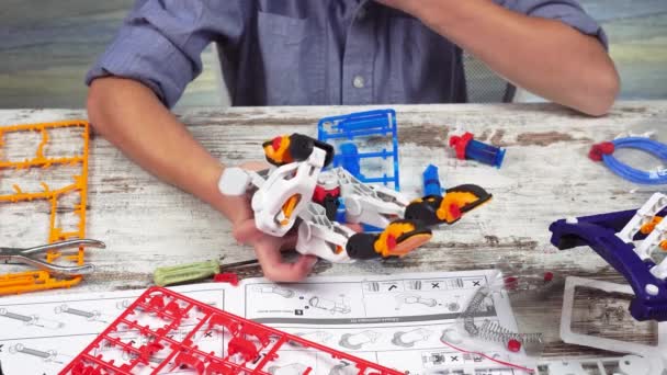 Niño juega con un juguete robótico montado por el diseñador. Montaje de un constructor de manipulador mecánico — Vídeos de Stock