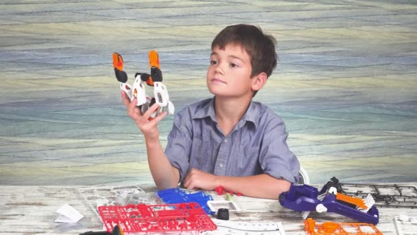 Niño juega con un juguete robótico ensamblado de diseñador. constructor innovador. — Vídeos de Stock