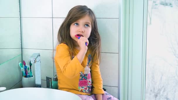 Meisje met tandenborstel, kijken in de grote spiegel, leren tanden poetsen — Stockvideo