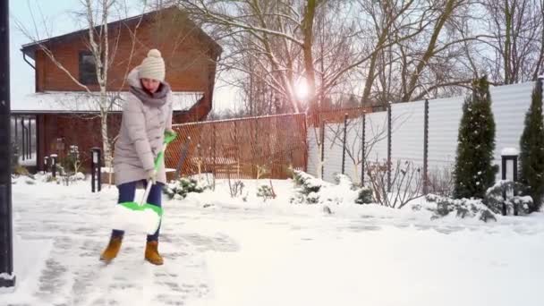 A woman cleans the path near the house from heavy snow. A shovel in hands. — Stockvideo