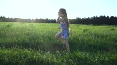 Bir kız yaz güneşinin altında çimlerin üzerinde yürüyor. jimnastik yapıyor.