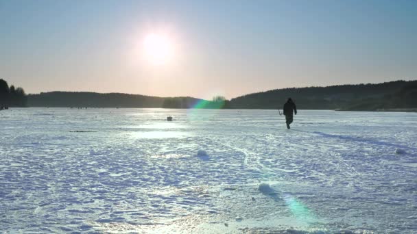 漁師は氷の上にいる。湖で冬の釣り。釣りの場を選ぶ. — ストック動画