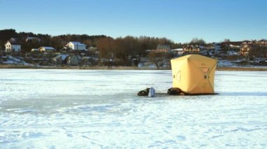 The fisherman sets up a tent on the ice for the winter fishing on the lake.