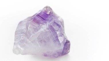 Ametist makro fotoğrafçılık. Beyaz arka planda mor şeffaf taş. Yüze ve vücuda mücevherlerle masaj. Alternatif tıp alanında mineral ve yarı değerli taşların kullanımı