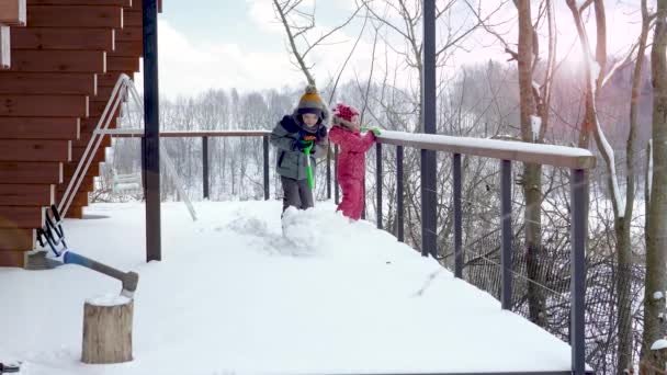 Barn rensar vägen nära huset från tung snö.Barn skyfflar snön — Stockvideo