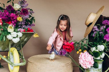 Gürültü efekti, bahar çiçekleriyle, bahçe aletleriyle ve hayvanlarla sevimli anaokulu kızı. Paskalya havası ve gerçek renkli çiçekler.