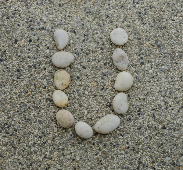 U - Letter alphabet stones laid out on the granite — Stock Photo, Image