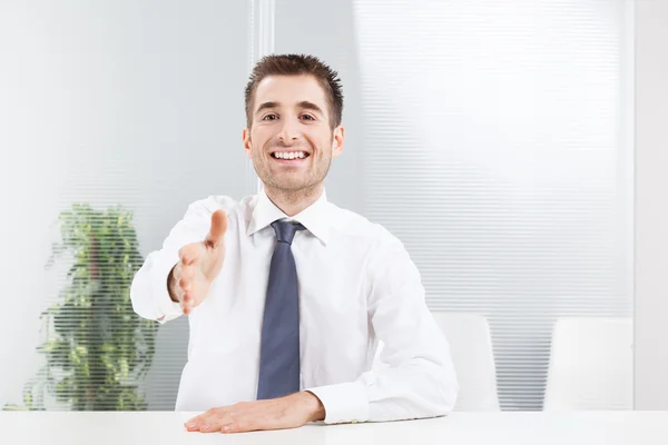 Junger Geschäftsmann per Handschlag vor hellem Hintergrund — Stockfoto