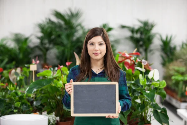 Zaměstnankyně zahradní drží prázdnou tabuli — Stock fotografie