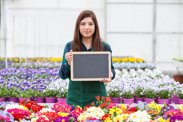 Zaměstnankyně zahradní drží prázdné chalkboar — Stock fotografie