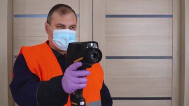 Sıcaklık kontrolü. Adam odaya girerken termal görüntüleyiciyle ısıyı kontrol ediyor. Hastalığın belirtilerinin tespiti. Vücut sıcaklığının uzaktan ölçümü.