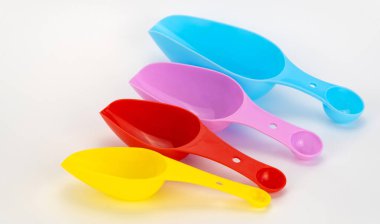 Beyaz arka planda mısır gevreği ve baharat için spatula. Toplu ürünler için renkli kepçeler