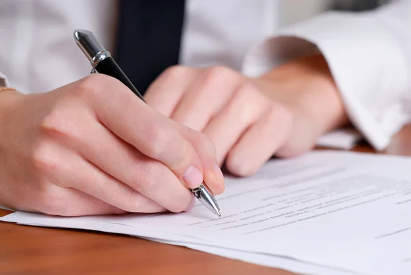 Person's hand signing an important document Stock Picture