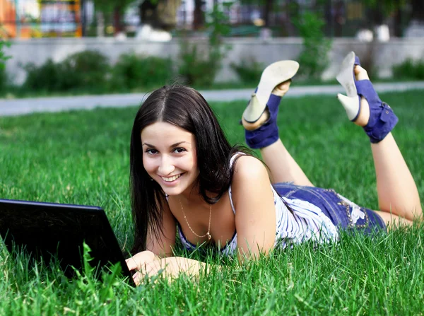 Encantadora morena con un portátil en el prado de verano —  Fotos de Stock