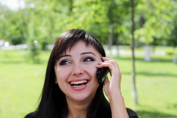 Jonge vrouw in het voorjaar park praten over de telefoon. — Stockfoto