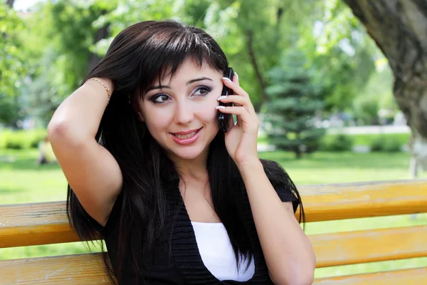 電話で話して春公園で若い女性. — ストック写真