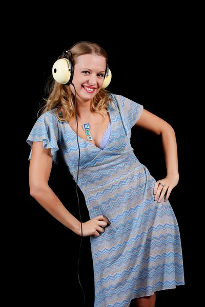 Una encantadora joven rubia sobre un fondo negro con auriculares — Foto de Stock