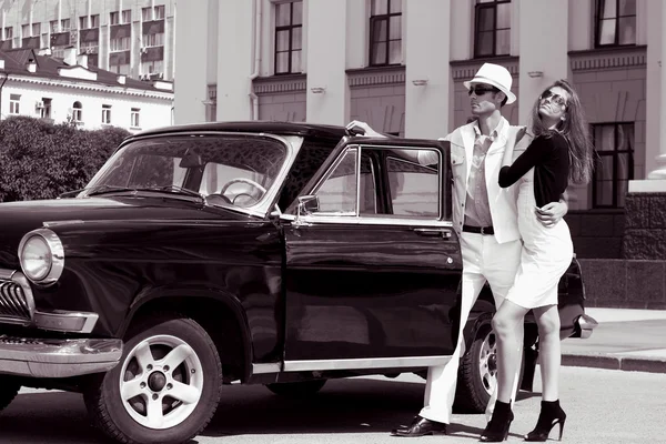 Un jeune couple avec une voiture rétro — Photo