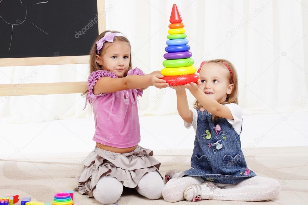 two little girls play with toys
