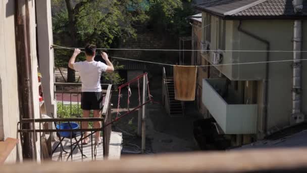 Людина вішає речі на балконі — стокове відео