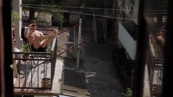 Чоловік засмагає на балконі — стокове відео