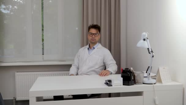 Médico Masculino Gira Silla Oficina Mira Cámara Través Sus Gafas — Vídeo de stock