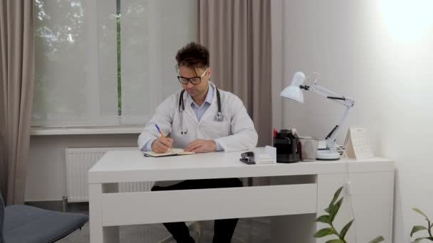 Homme Médecin Dans Des Lunettes Écrit Des Données Dans Carnet — Video