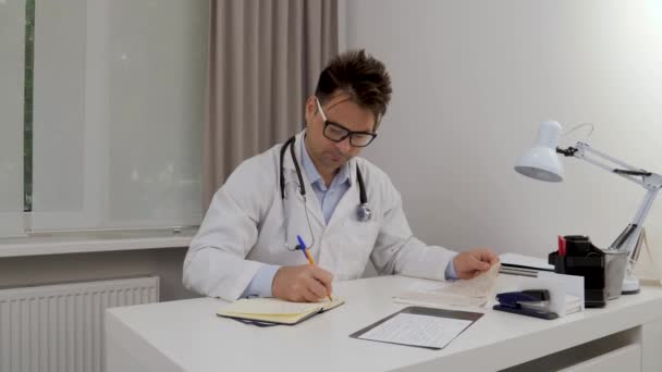 Doktor Ofisteki Beyaz Bir Masaya Otururken Bir Deftere Yazıyor — Stok video