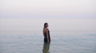 girl in a black evening dress goes towards the horizon standing