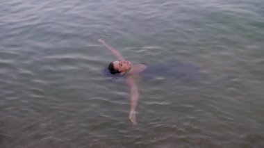 Siyah elbiseli kız kollarını yanlara doğru açıyor.