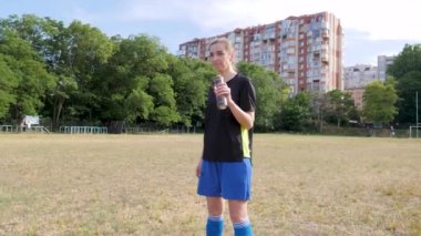 soccer player girl drinks water at the old stadium
