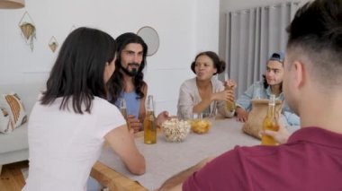 a group of friends sits at the table, a guy with long hair tells the rest of the story to his society